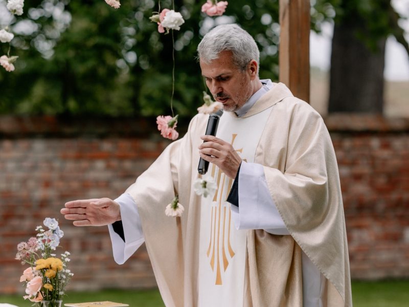 Ksiądz z mikrofonem podczas mszy w plenerze Oklaski